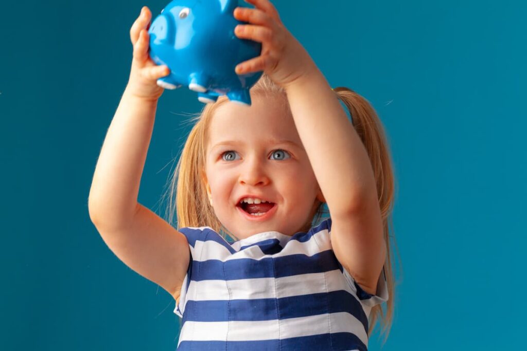 Kind met spaarvarken, blij, blauwe achtergrond.