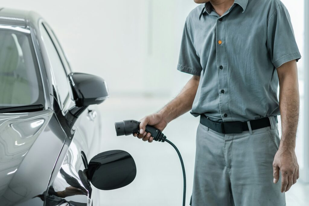 Senior asian Technician is charging the electric car or EV in service center for maintainance