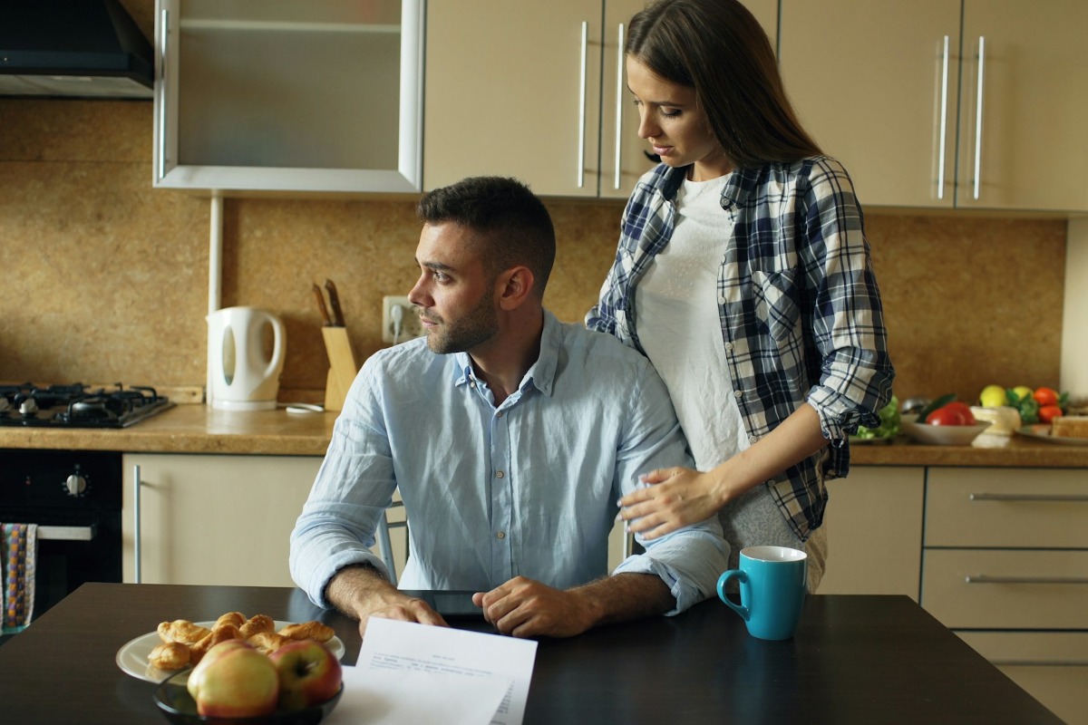 Twee personen bespreken financiële documenten aan de keukentafel.