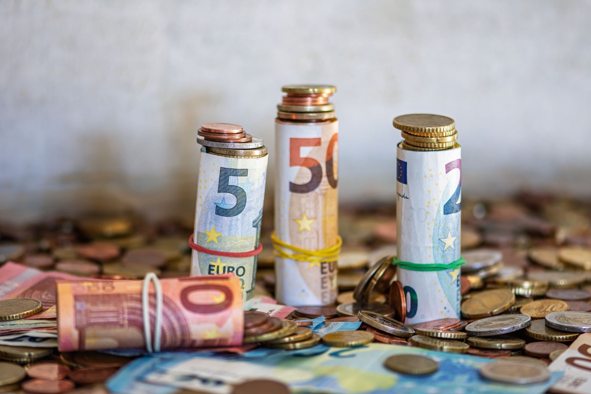 Opgerold eurobiljetten en munten op tafel, symbool voor sparen en geldwaarde.
