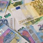 Losse eurobiljetten in verschillende waardes liggen verspreid op een tafel.