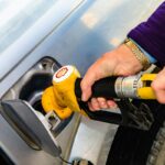 Automobilist vult de brandstoftank bij een pomp op het tankstation